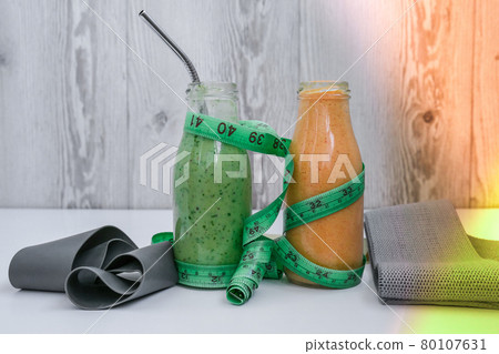 Seasonal Matcha green vegan smoothie and pumpkin carrot smoothie drink detox Breakfast with measuring tape and rubber resistance band. Stretch fitness band. Clean eating, weight loss, healthy dieting Seasonal Matcha green vegan smoothie and pumpkin carrot smoothie drink detox Breakfast with measuring tape and rubber resistance band. Stretch fitness band. Clean eating, weight loss, healthy dieting 80107631