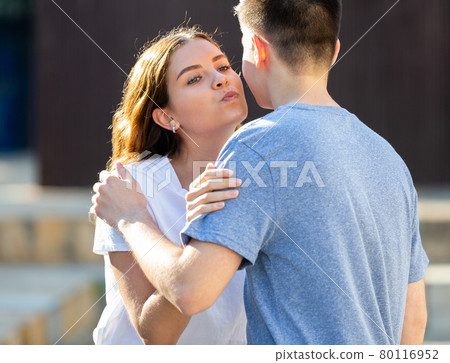 Kiss on cheek of boy and girl on street of summer city 80116952
