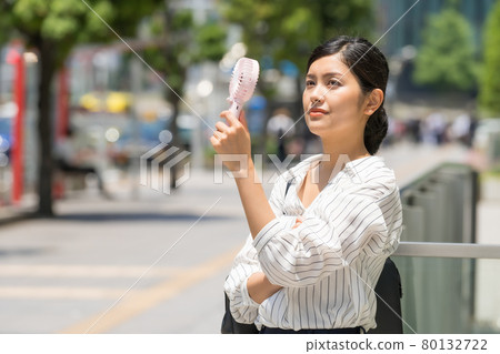 Mini fan in the business district (business woman with a handy fan) Mini fan in the business district (business woman with a handy fan) 80132722