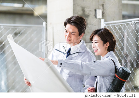 Men and women inspecting while looking at drawings at the construction site Men and women inspecting while looking at drawings at the construction site 80145131