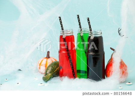 Halloween drink. Black Red Green cocktail in glass jar decorated with  straws, pupmkins on blue, creative idea for Home party, funny food, spooky toxic drink for kids, seasonal menu 80156648