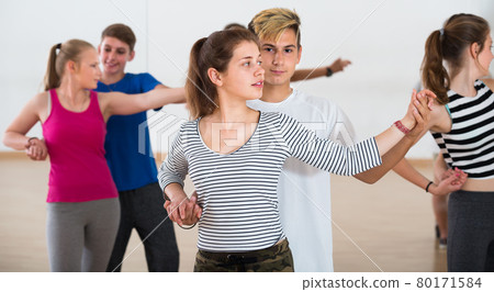 Group of satisfied teen dancing tango in dance studio Group of satisfied teen dancing tango in dance studio 80171584