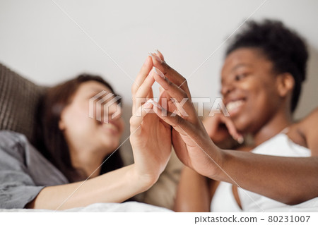 Hands of happy lesbian females relaxing in bed 80231007