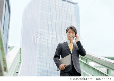 Portrait of a middle-aged businessman having a conversation on a smartphone in an office building area Portrait of a middle-aged businessman having a conversation on a smartphone in an office building area 80244863