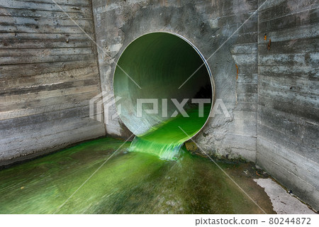 Bright green polluted effluent flowing through a drainage pipe 80244872