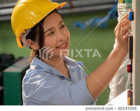 Female manufacturing factory worker using a tablet computer checking machine operation in a beverage factory production line.. Female manufacturing factory worker using a tablet computer checking machine operation in a beverage factory production line.. 80245008