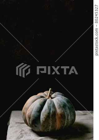 Blue pumpkin on linen tablecloth. Dark still life 80245327