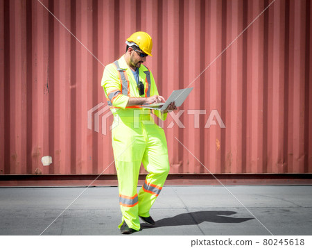 Inspection Asian engineer is using a laptop computer and wearing a yellow safety helmet and check for control loading containers box from Cargo freight ship for import and export.. Inspection Asian engineer is using a laptop computer and wearing a yellow safety helmet and check for control loading containers box from Cargo freight ship for import and export.. 80245618
