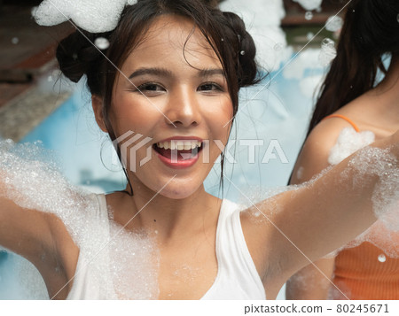 Portrait of pretty young woman in bikini having fun on soap foam disco party in the swimming pool.. Portrait of pretty young woman in bikini having fun on soap foam disco party in the swimming pool.. 80245671