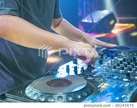 Disc Jokey Hands on a sound mixer station and vinyl in the nightclub at a party. Nightlife at the club, party concept. Disc Jokey Hands on a sound mixer station and vinyl in the nightclub at a party. Nightlife at the club, party concept. 80245673