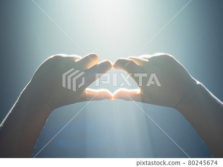A beam of neon light from the pub shines through a young man's hand with a heart symbol. Hands in shape of love heart A beam of neon light from the pub shines through a young man's hand with a heart symbol. Hands in shape of love heart 80245674