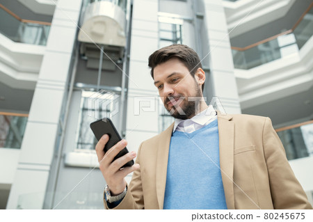Businessman reading a message on the phone 80245675