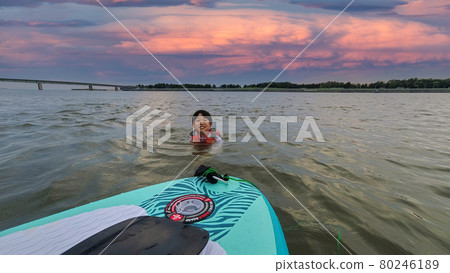 一個可愛的孩子在夏天的海裡玩 SUP 板和美麗的日落風景 一個可愛的孩子在夏天的海裡玩 SUP 板和美麗的日落風景 80246189