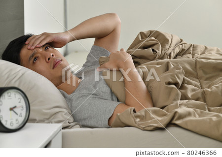 Depressed young Asian man lying in bed cannot sleep from insomnia Depressed young Asian man lying in bed cannot sleep from insomnia 80246366