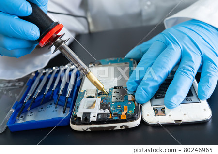 Technician repairing inside of mobile phone by soldering iron. Integrated Circuit. the concept of data, hardware, technology. Technician repairing inside of mobile phone by soldering iron. Integrated Circuit. the concept of data, hardware, technology. 80246965