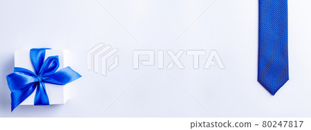 Father day gift. White box with bow ribbon, blue bowtie or tie on light background. Concept of Fathers Day greeting card, copy space for text. 80247817