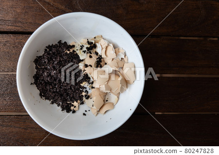 Overhead view of crushed egg shell and spent coffee grounds in bowl. Natural organic fertilizers for gardening rich in nitrogen, calcium and potassium 80247828