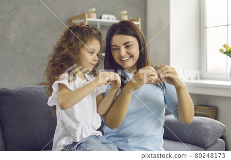 Happy mother and little daughter smiling to each other and doing hand heart gesture 80248173