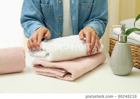 Young woman folds clean towels, close up Young woman folds clean towels, close up 80248218