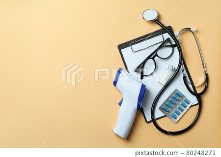 Medical tools and thermometer gun on beige background Medical tools and thermometer gun on beige background 80248271