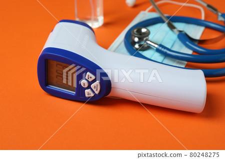 Medical tools and thermometer gun on orange background Medical tools and thermometer gun on orange background 80248275