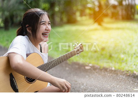 beautiful girl playing guitar at the garden beautiful girl playing guitar at the garden 80248614