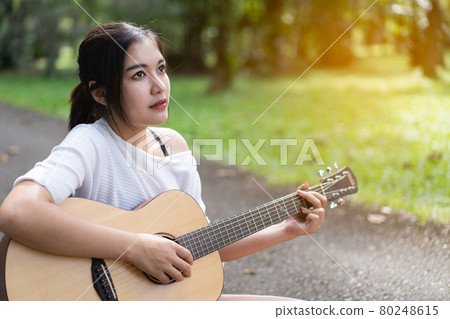 beautiful girl playing guitar at the garden beautiful girl playing guitar at the garden 80248615