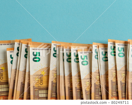 Orange 50 euro paper banknotes in a row against blue background. Copy space. 80249711