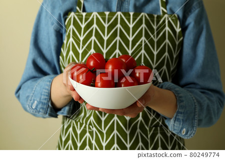 Woman hold bowl with cherry tomato against beige background Woman hold bowl with cherry tomato against beige background 80249774