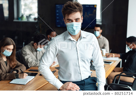 Young businessman in mask sitting on desk and posing 80251714