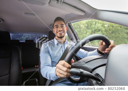 Smiling arab guy driving his car, shot from dashboard Smiling arab guy driving his car, shot from dashboard 80252068