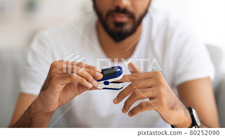 Unrecognizable man using pulse oximeter at home 80252090