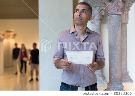 Adult male is visiting at the exposition with brochure 80253306