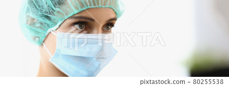 The female doctor wears a protective mask and cap 80255538