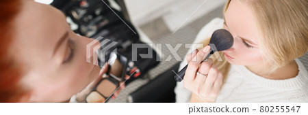 Woman in salon applies powder to blonde with brush Woman in salon applies powder to blonde with brush 80255547