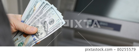 A man withdraws cash on the street at an ATM 80255579