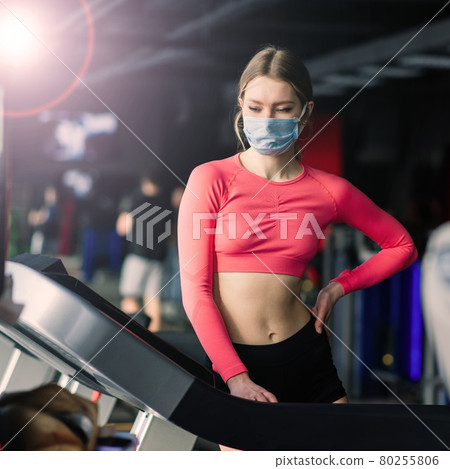 Woman wearing face mask exercise workout in gym during corona virus pandermic. 80255806