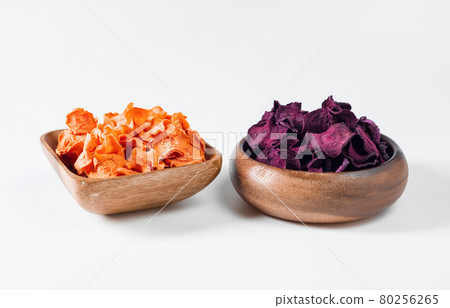 Dried carrot and beet chips in a wooden bowl on a white background. Vegetarian diet food. Horizontal orientation. Dried carrot and beet chips in a wooden bowl on a white background. Vegetarian diet food. Horizontal orientation. 80256265