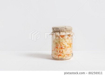 Homemade sauerkraut. Fermented food. Sauerkraut with carrots in a glass jar on a white wooden background Homemade sauerkraut. Fermented food. Sauerkraut with carrots in a glass jar on a white wooden background 80256911