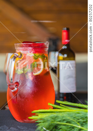 Lunch with a decanter of chilled red fruit drink with lemon wedges. A bottle of wine and herbs. 80257202