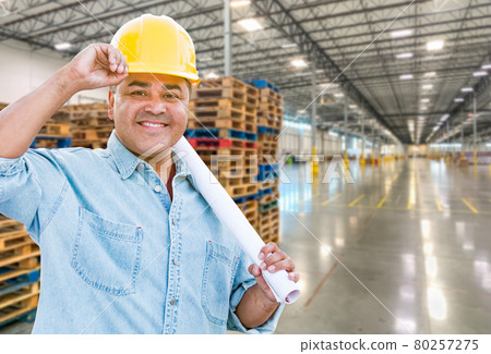 Hispanic Male Contractor Wearing Hard Hat Standing in Empty Industrial Warehouse. 80257275