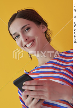 Portrait of young girl with happy face while using smartphone isolated on pink background Portrait of young girl with happy face while using smartphone isolated on pink background 80258146