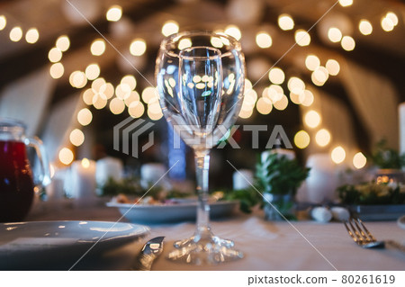 Two glasses on table on white tablecloth on blurred warm lights background 80261619