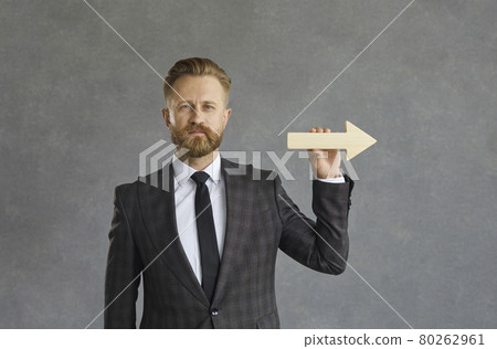 Confident businessman in suit holding arrow pointing to right studio shot 80262961