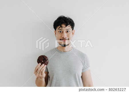 Happy man holding a chocolate cookie isolated on white background. 80263227