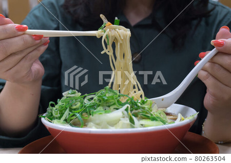 Woman eating vegetable ramen 80263504