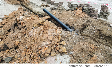 Laying installation of a new cable in a plastic pipe. Digging drilling of the earth for pipe replacement, sewer.Work with drainage system, water supply and electric cable laying. 80265662