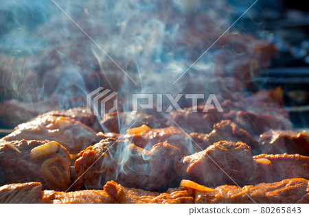 Cooking barbecue on the grill with smoke. Cook fresh marinated meat with onions. Grill marinated barbecue is prepared on the grill on the coals. Morning BBQ. Meat on grill. 80265843