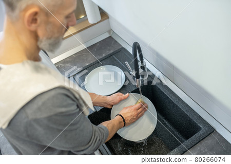 Close up of a man washing the plates in the kitchen 80266074