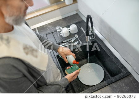 Close up of a man washing the plates in the kitchen 80266078